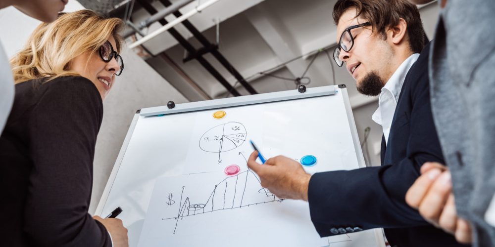 Businesspeople with whiteboard discussing strategy in a meeting. Close view